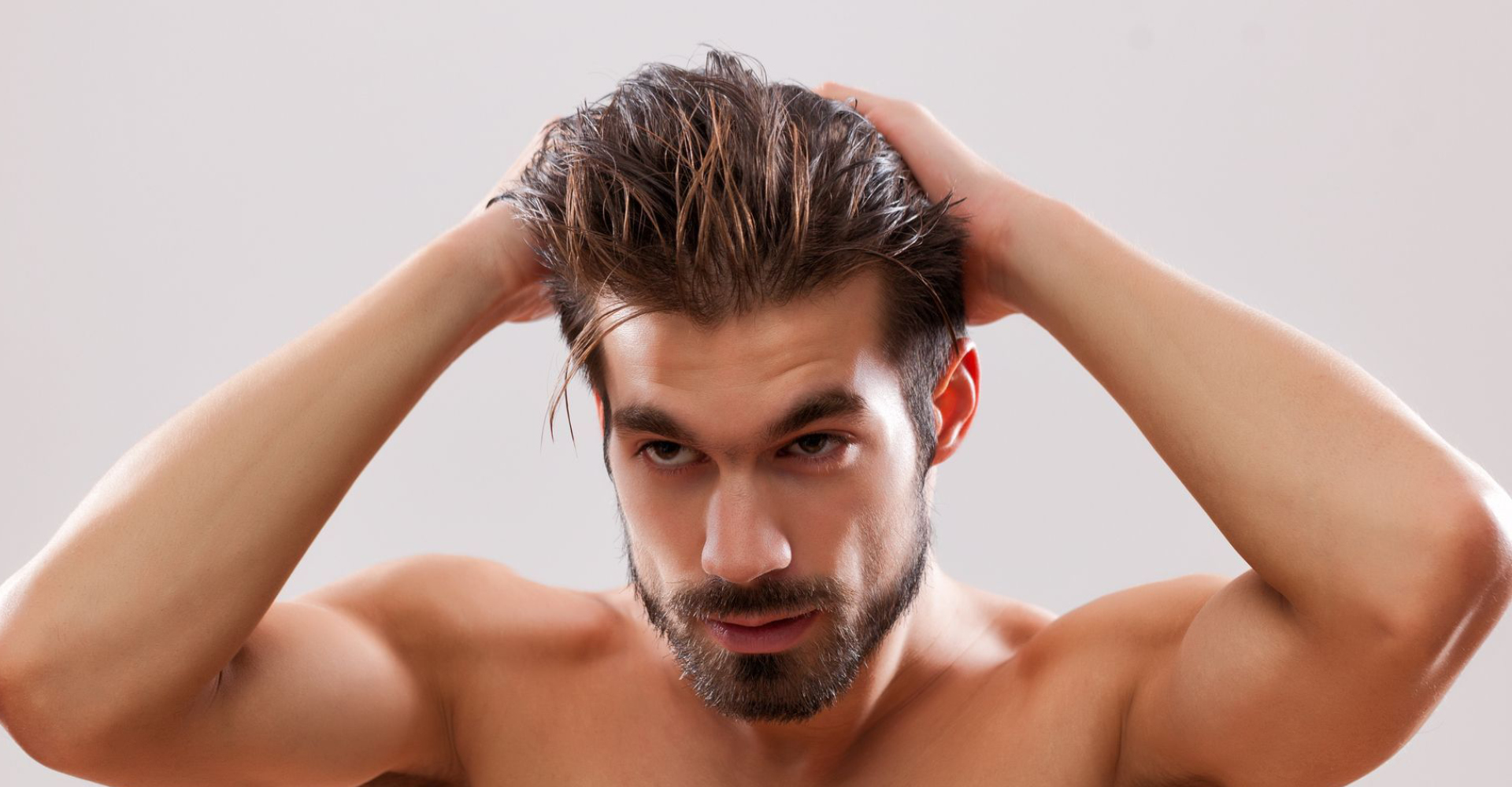 immagine di un uomo che si tocca i capelli con appena messa la cera nei capelli abbastanza lunghi